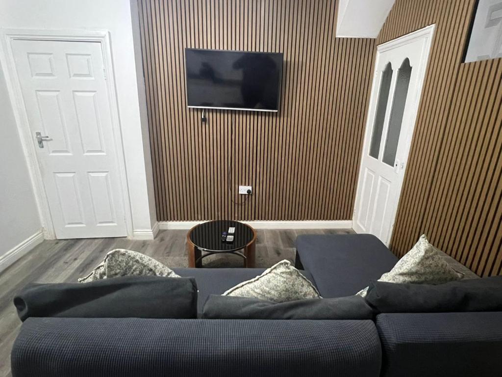 a living room with a couch and a tv on a wall at Femros Apartments, 15mins to city center. in Smethwick