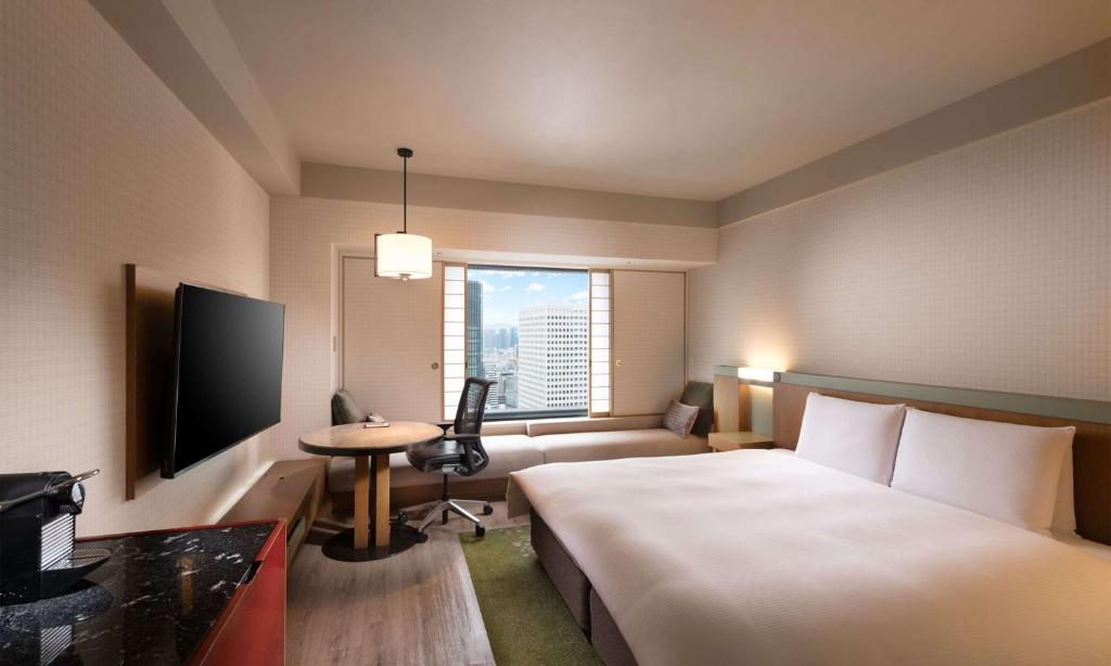 a hotel room with a bed and a desk and a television at Hilton Osaka Hotel in Osaka