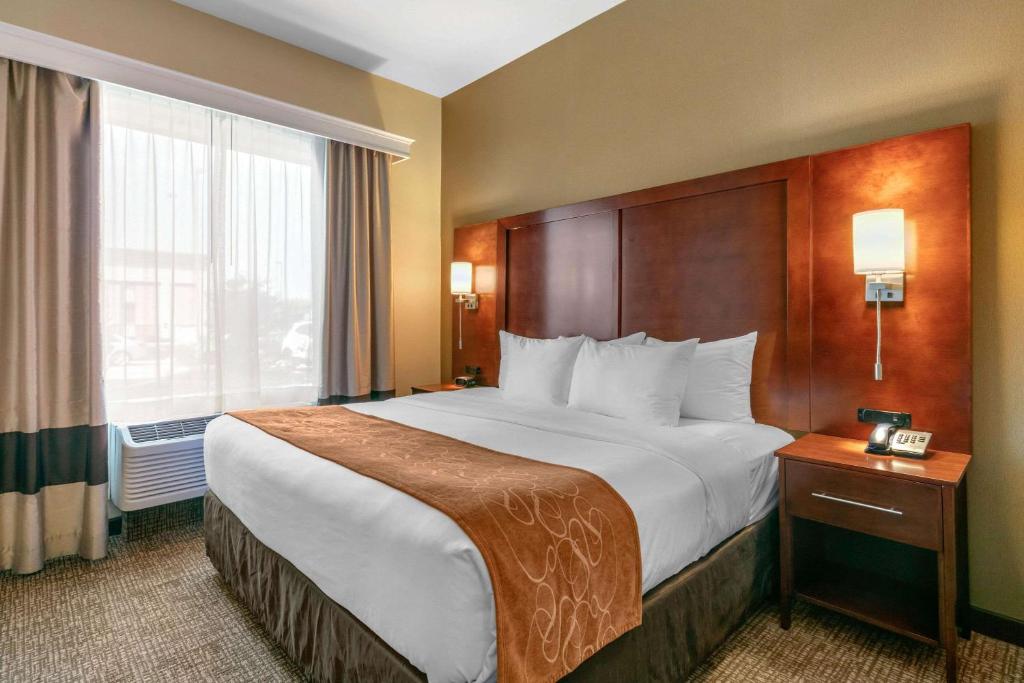 a hotel room with a large bed and a window at Comfort Suites in Forrest City