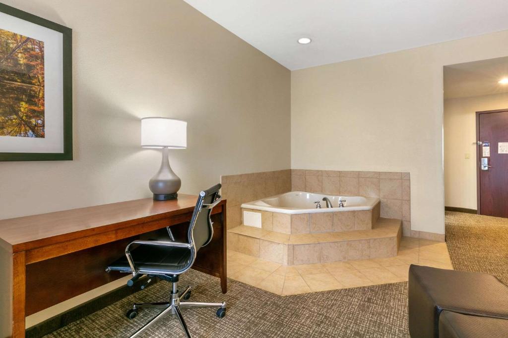 a room with a tub and a desk and a chair at Comfort Suites in Forrest City
