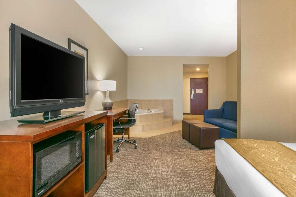 a hotel room with a bed and a flat screen tv at Comfort Suites in Forrest City