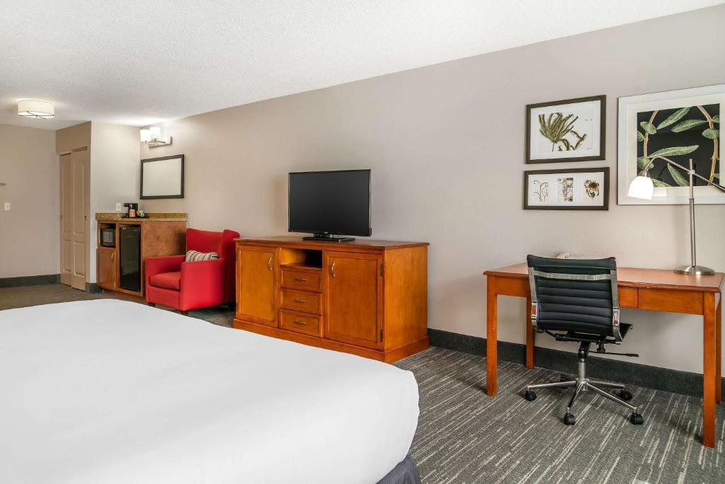a hotel room with a bed and a desk and a television at Country Inn & Suites by Radisson, Rossford - Toledo South in Rossford