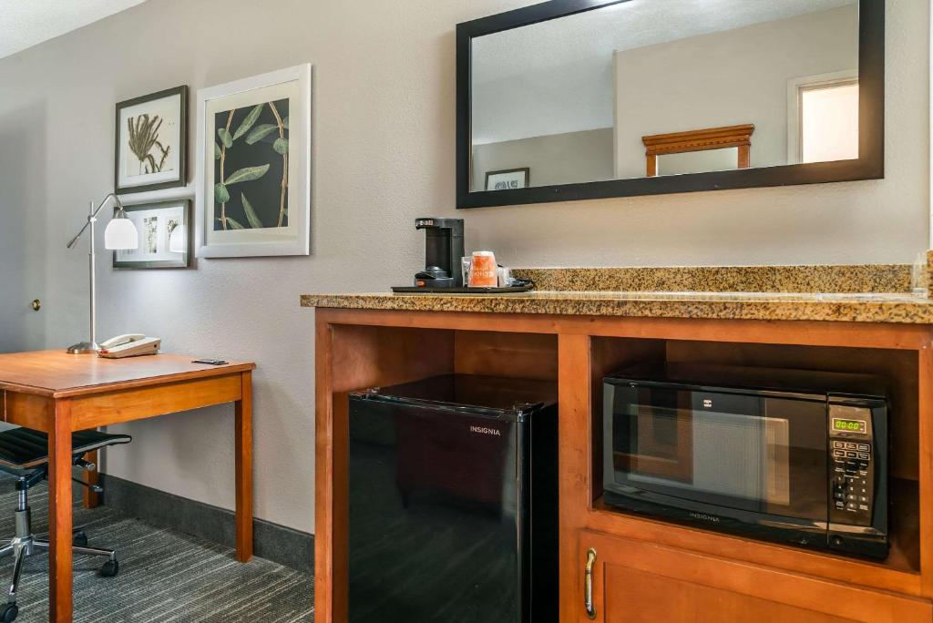 a kitchen with a microwave and a desk in a hotel room at Country Inn & Suites by Radisson, Rossford - Toledo South in Rossford
