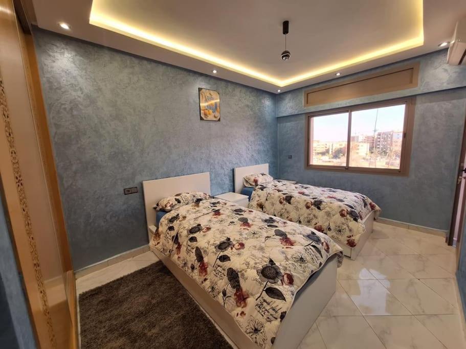 a bedroom with two beds and a window at Jardin Majorel Appartement en résidence fermée in Marrakech