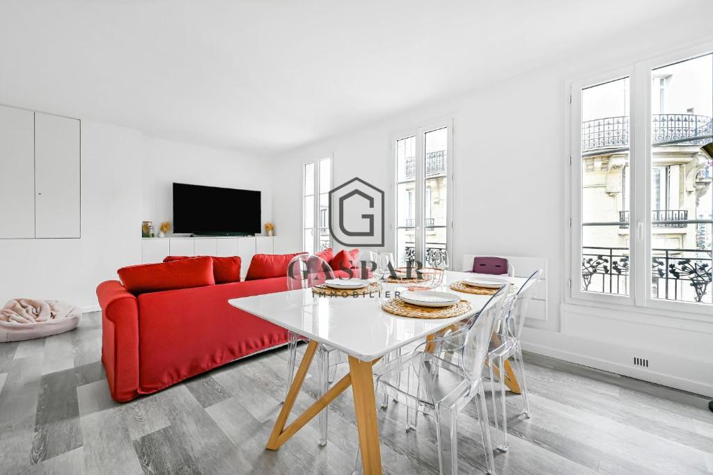 a living room with a red couch and a table at GASPAR - Appartement 2 Chambres 4 personnes Dernier étage 75 m2 in Boulogne-Billancourt