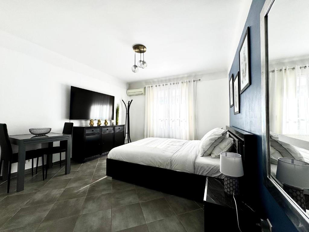 une chambre avec un lit, une table et une télévision dans l'établissement Studio vue mer terrasse à 1min des plages, à Juan-les-Pins