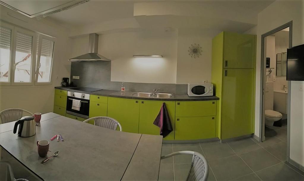a kitchen with green cabinets and a table with chairs at Le Repaire in Cormaranche-en-Bugey