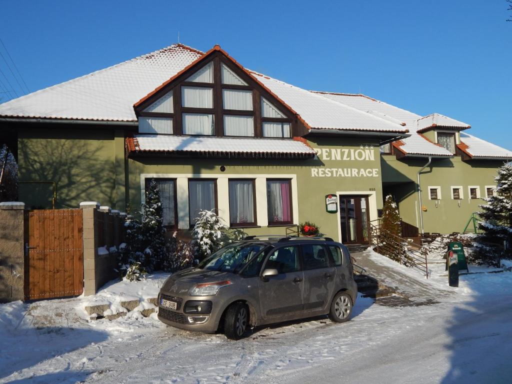 a car parked in front of a house in the snow at Penzion U Kašných in Mníšek pod Brdy