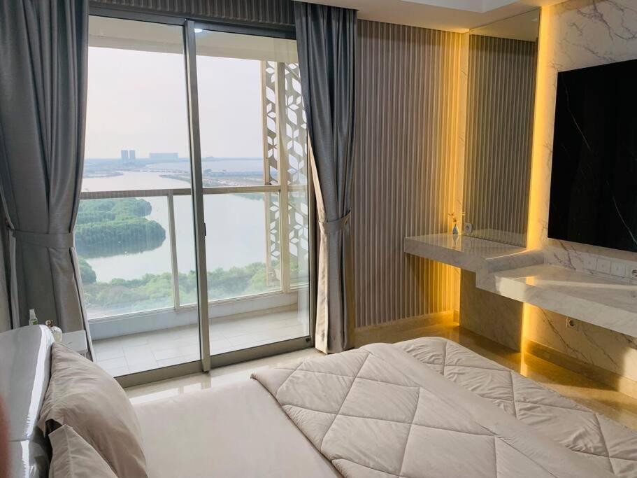 a bedroom with a bed and a large window at Apartment Goldcoast-Studio Room in Jakarta