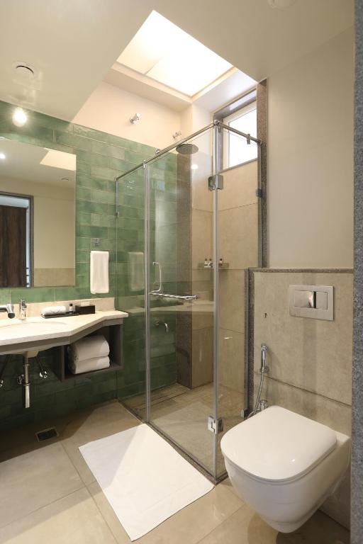 a bathroom with a shower and a toilet and a sink at Golden Fields Resort in Mulshi