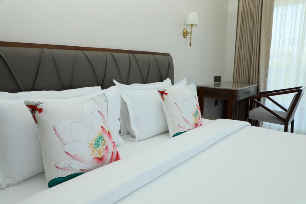 a bedroom with a white bed with white pillows at Golden Fields Resort in Mulshi