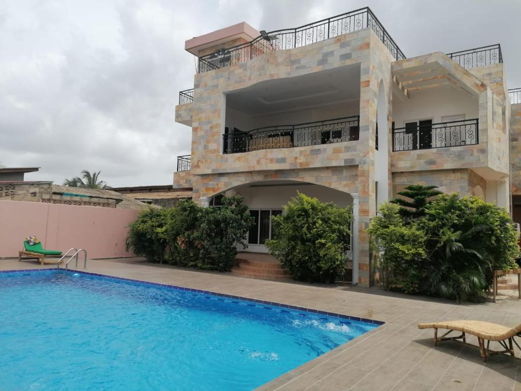 a villa with a swimming pool in front of a building at Belle location familiale in Abomey-Calavi