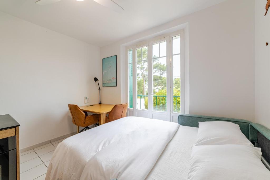 une chambre blanche avec un lit et un bureau dans l'établissement Cocon comfortable vue mer, Clim et parking, à Sanary-sur-Mer