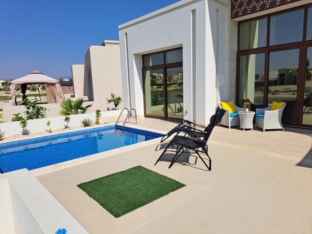 a villa with a swimming pool and a chair at Villa Laguna Lux TU10 in Salalah