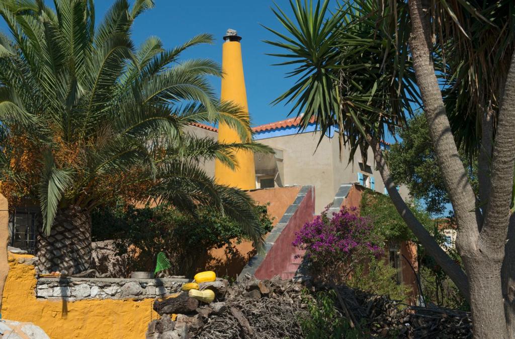 a building with a lighthouse in the background with palm trees at Painter's Country House in Logothetiánika