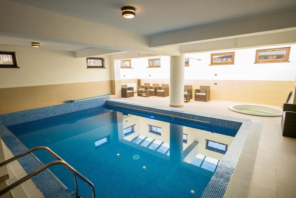 a large swimming pool in a bathroom with a tub at Pensiunea Royal Spa in Piatra Neamţ