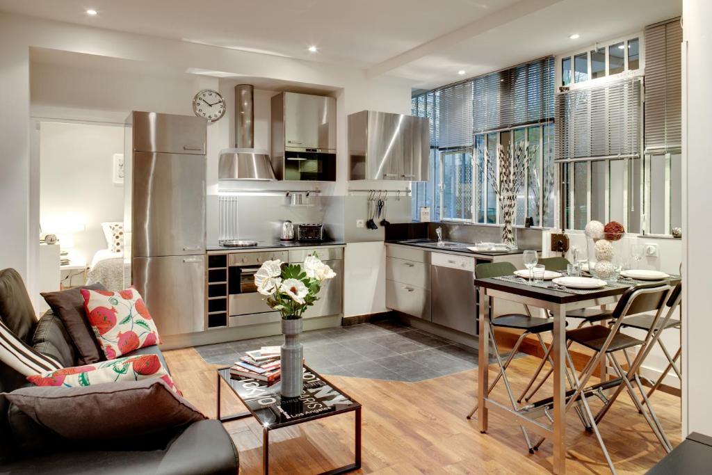 une cuisine et un salon avec un canapé et une table dans l'établissement Beauregard central residence, à Paris