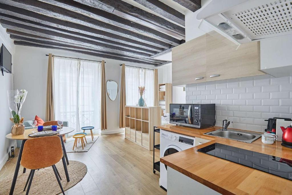 une cuisine avec un comptoir et une table avec des chaises dans l'établissement Charming Studio Center of Paris, à Paris