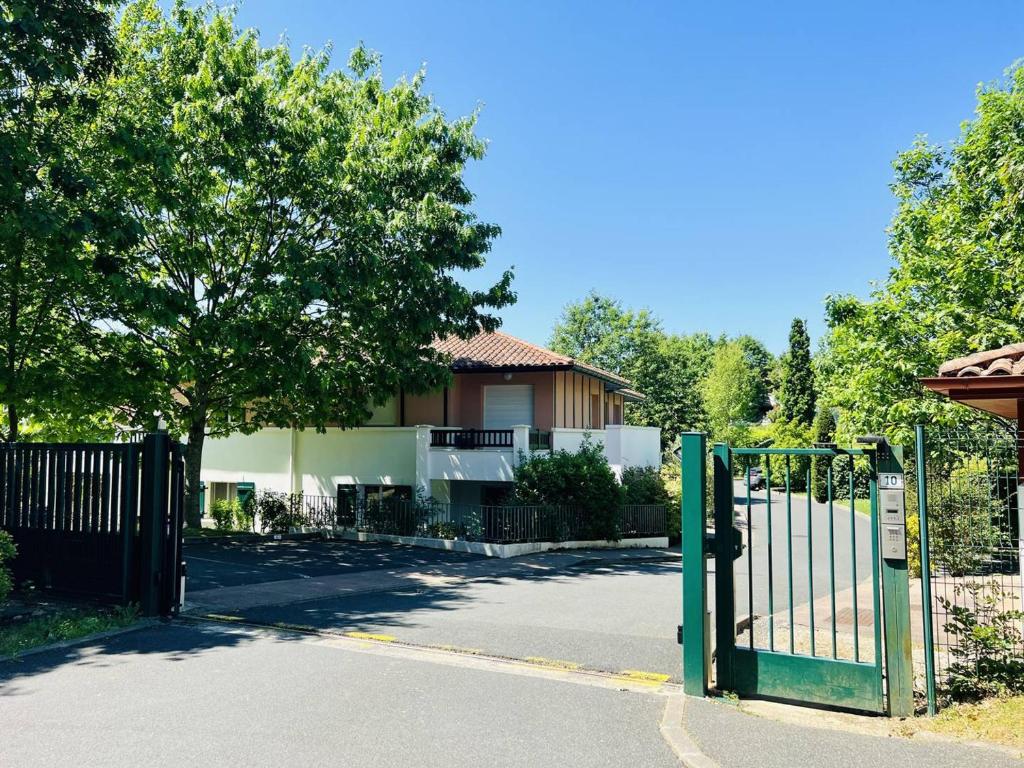 a green gate in front of a house at Appartement T2 à Cambo-les-Bains, RDC, piscine, proche thermes, wifi, parking privé, non-fumeur. - FR-1-495-33 in Cambo-les-Bains