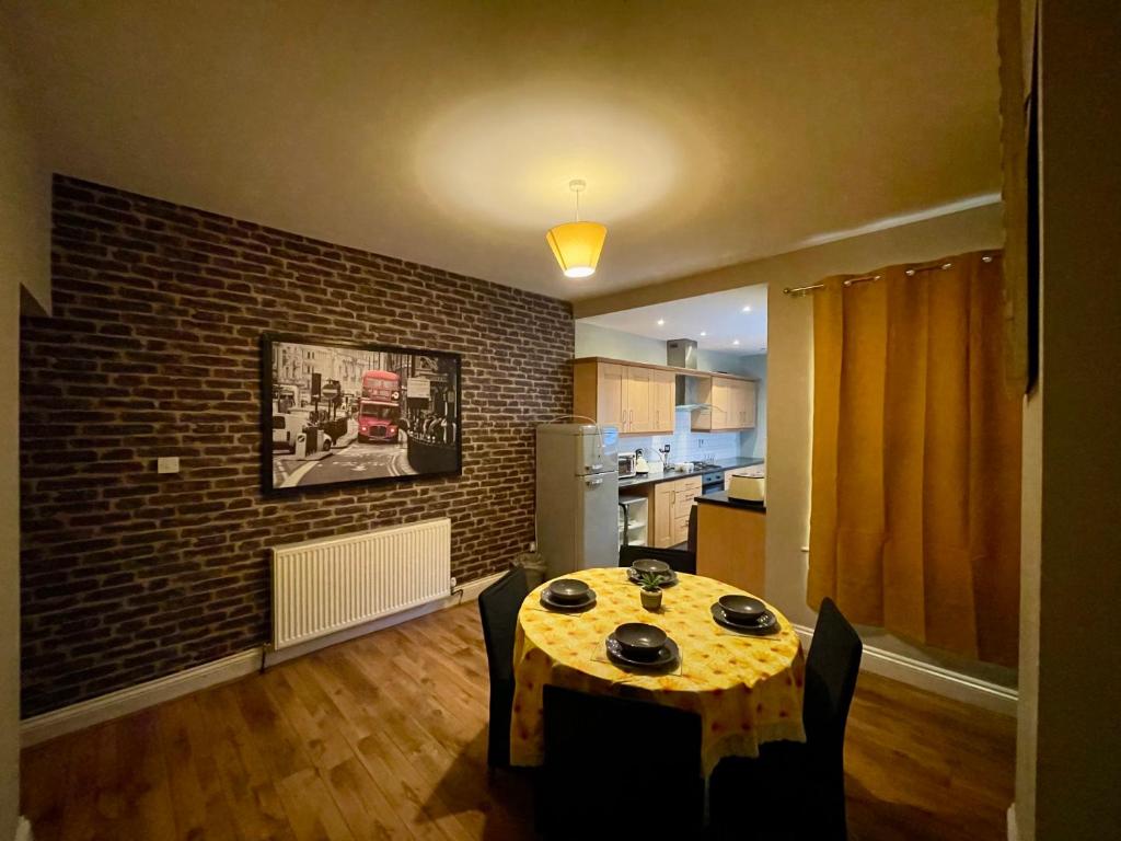 a kitchen with a table and a brick wall at Stylish 3-Bedroom Home! in Bedworth