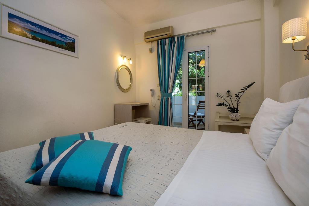 a bedroom with a white bed with a blue and white pillow at Diamond Apartments & Suites in Hersonissos