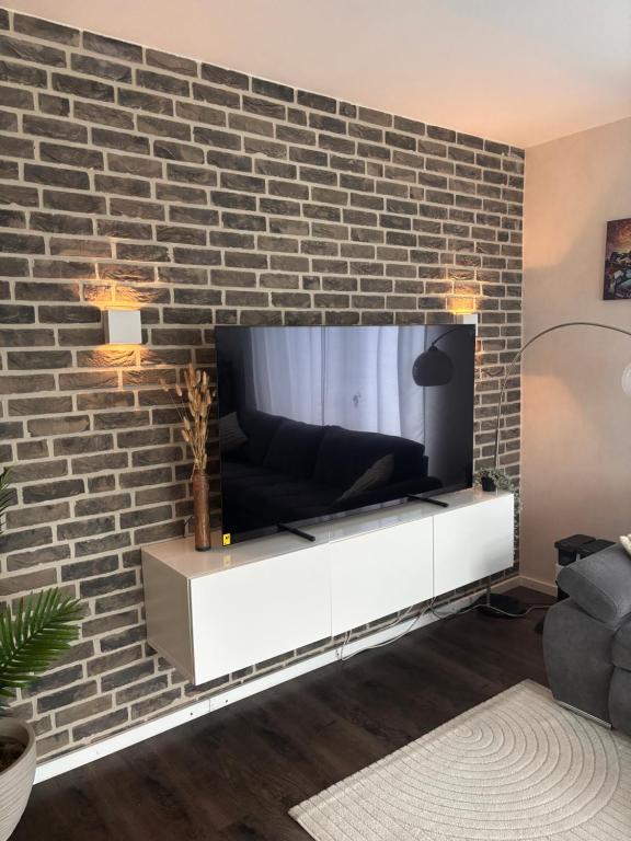a living room with a tv on a brick wall at Familienfreundliche Unterkunft in Rietberg