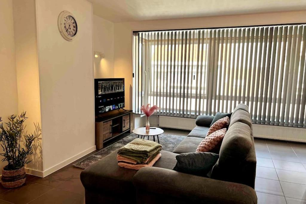 a living room with a couch and a large window at Bright, spacious apartment nearby beach in Ostend