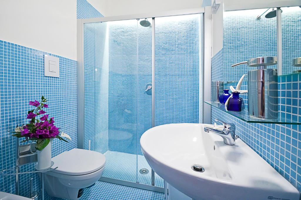 bagno piastrellato blu con lavandino e servizi igienici di Palazzo Coccoli a Santa Maria di Castellabate