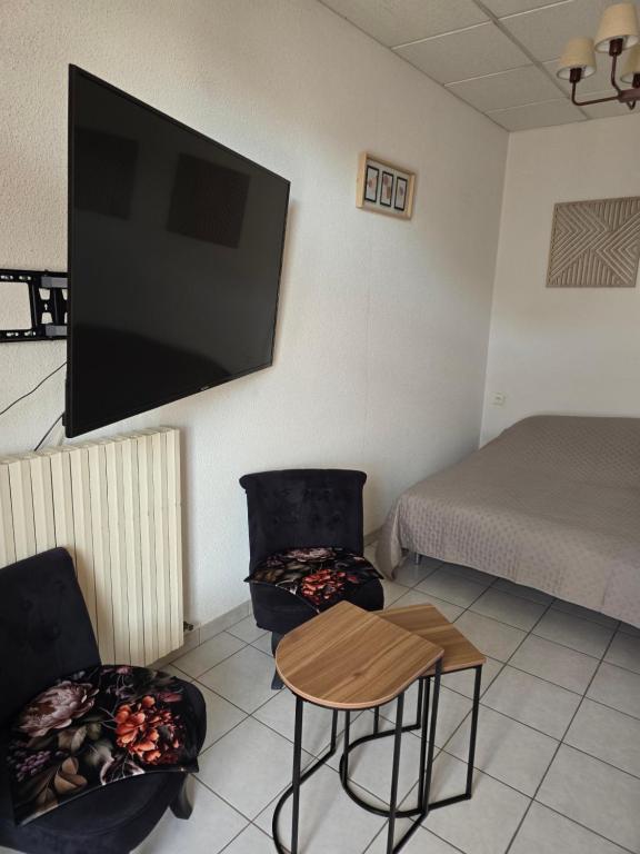 a room with two chairs and a television on the wall at Chambre indépendante in Les Avenières