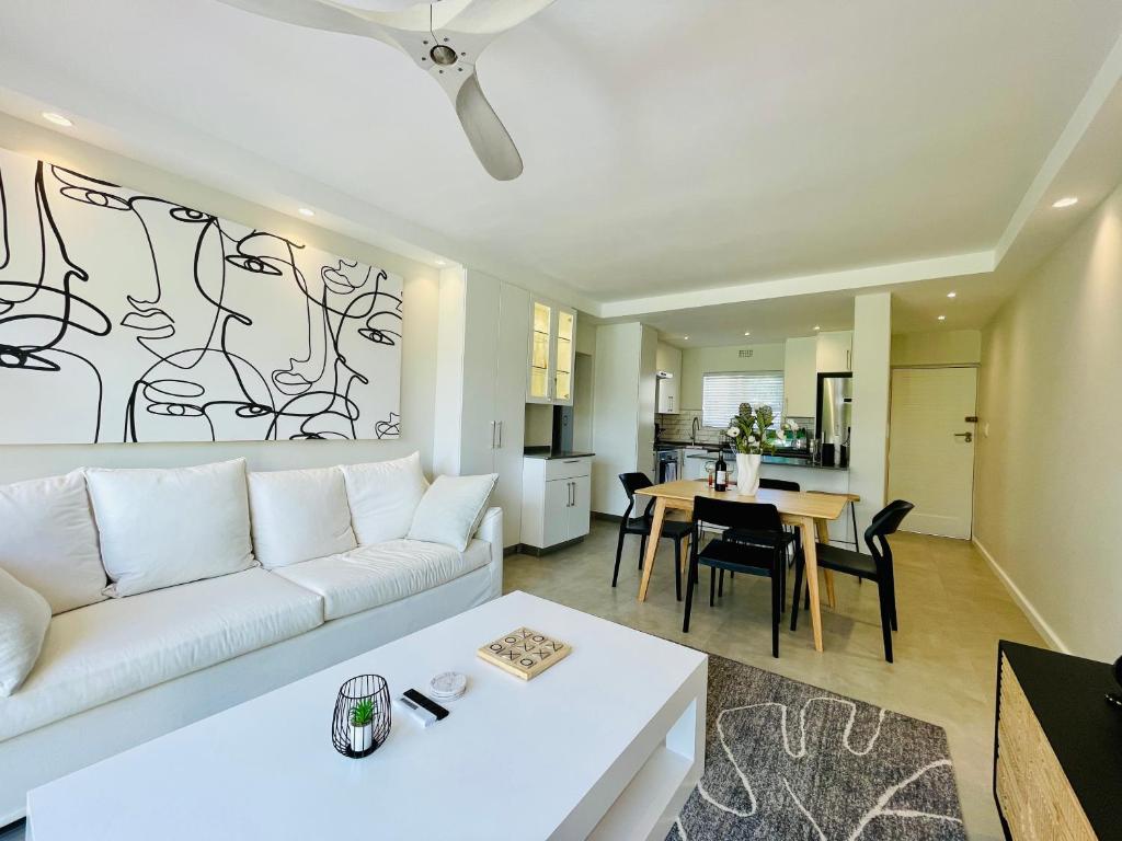 Una sala de estar con un sofá blanco y una mesa. en Tranquility Place - Goose Valley, en Plettenberg Bay