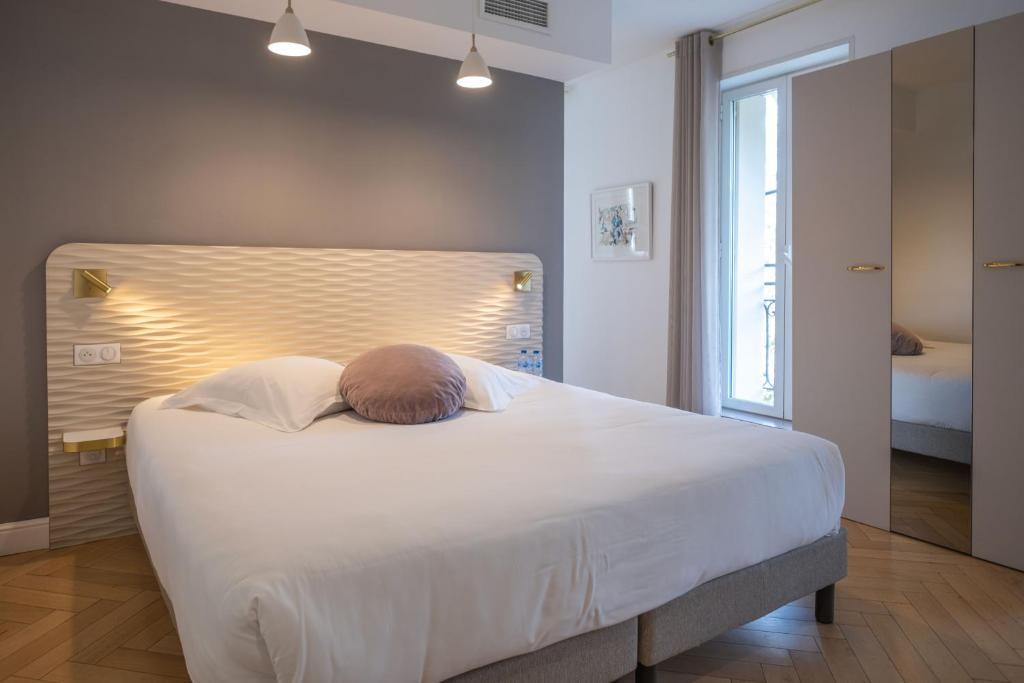 a bedroom with a large white bed and a window at Hôtel le XIX in Béziers