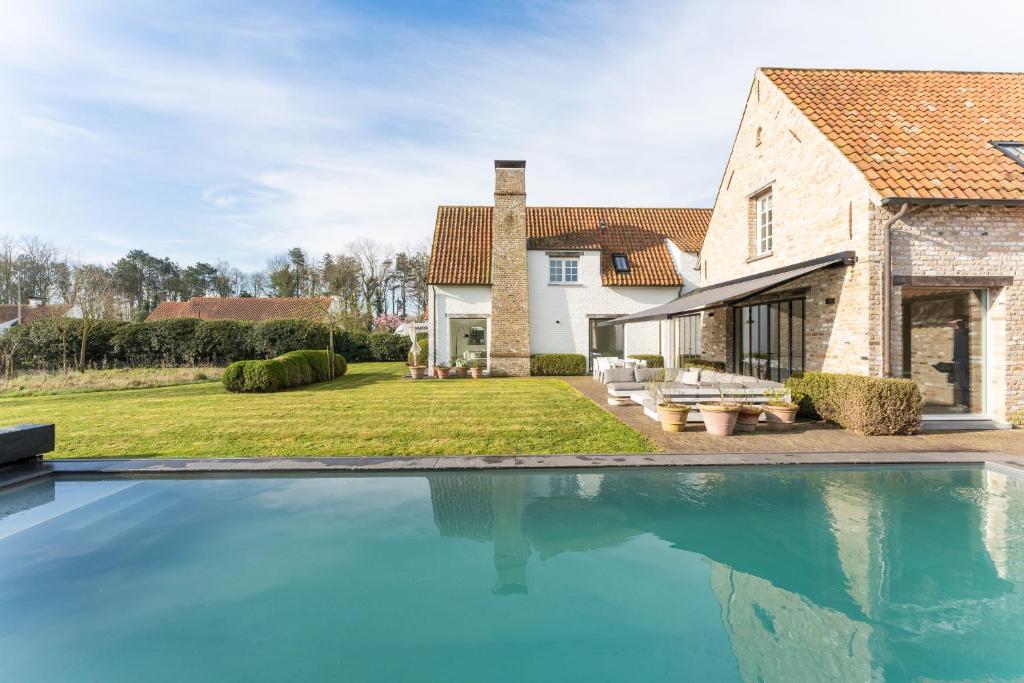 a house with a swimming pool in front of a house at Endless summer Knokke - Pool Villa in Knokke-Heist