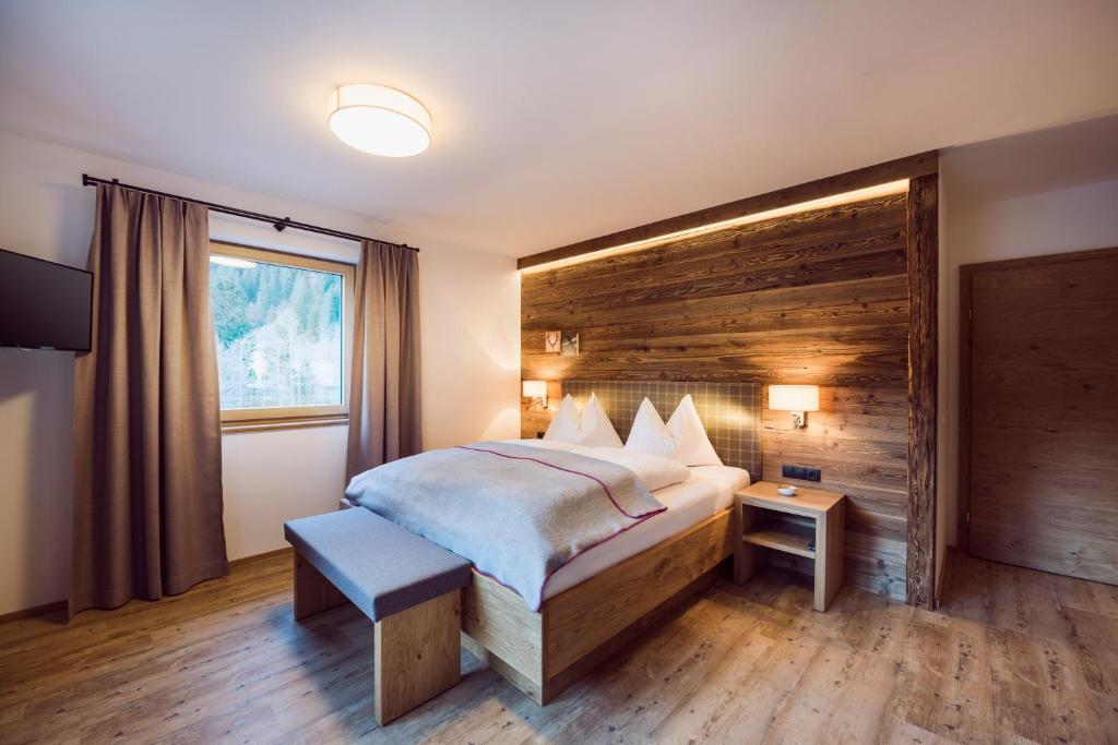 a bedroom with a large bed with a wooden wall at stoanmandl Wohlfühlappartements in Neustift im Stubaital