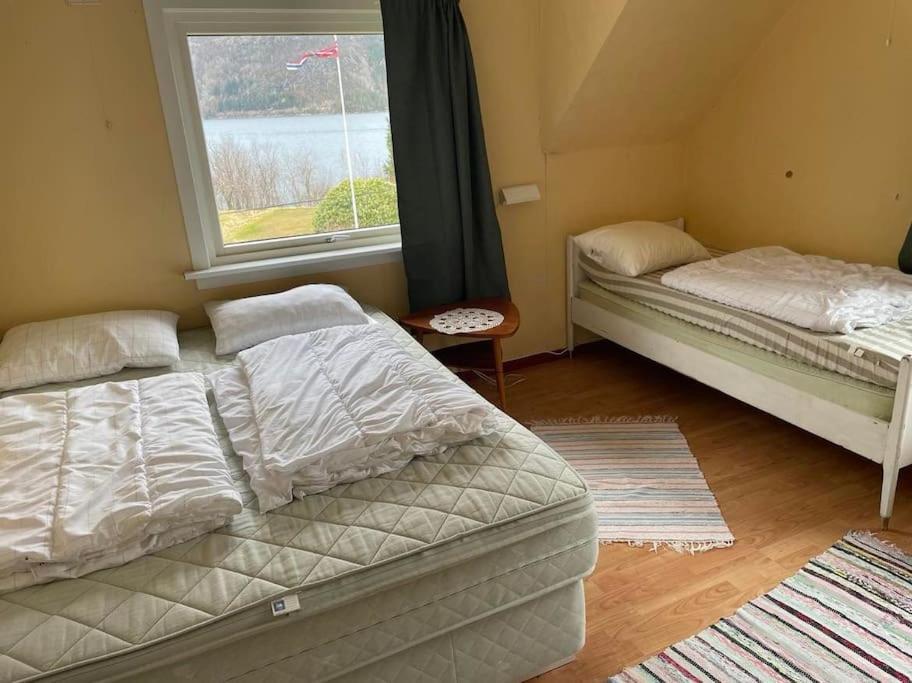 Dos camas sentadas en una habitación con ventana. en Oceanview House Ideal for Peaceful Holidays, en Venøya