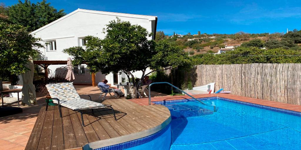 a person sitting on a deck next to a swimming pool at Casa Luna in Tolox