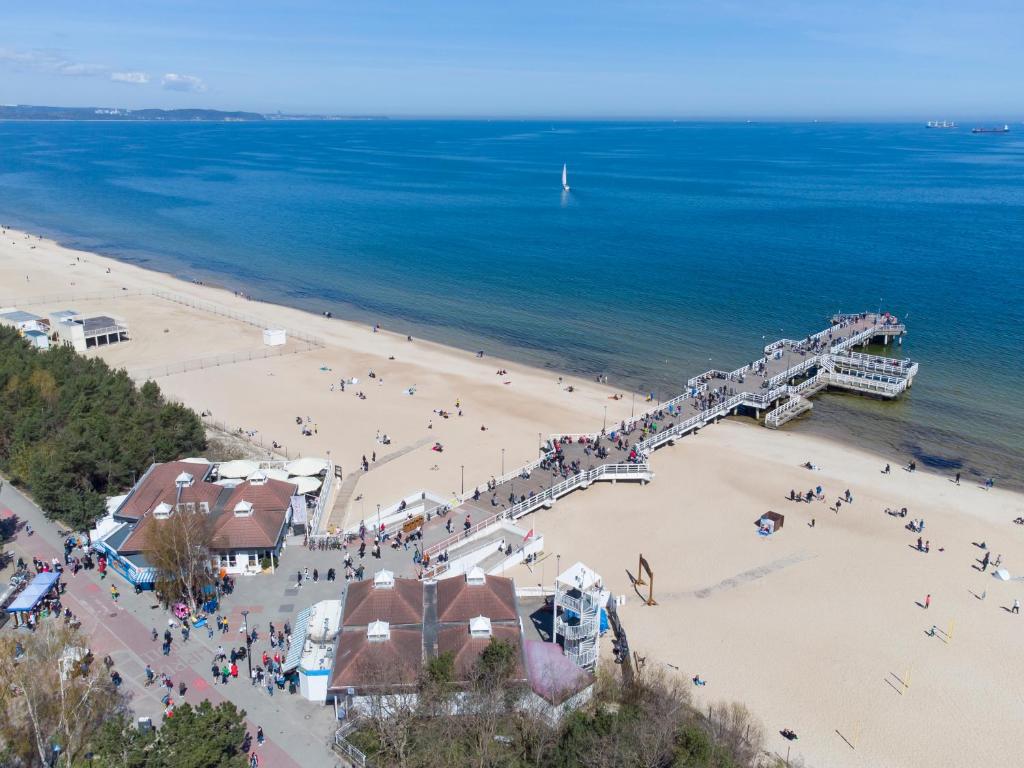 eine Gruppe von Menschen am Strand in der Nähe eines Piers in der Unterkunft Apartament Sea & Sun Letnica in Danzig