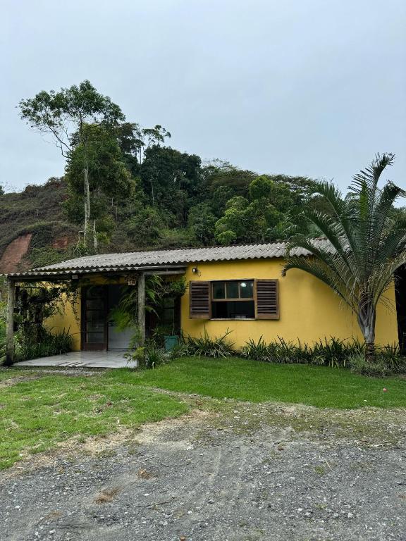 a yellow house with a palm tree in front of it at O refugio do beija-flor in Angra dos Reis