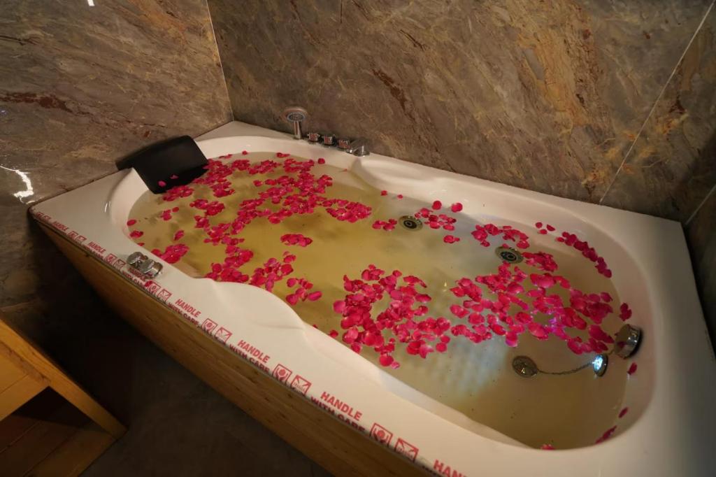 a white bath tub with pink sprinkles on it at DSR Wooden Cottages in Hyderabad