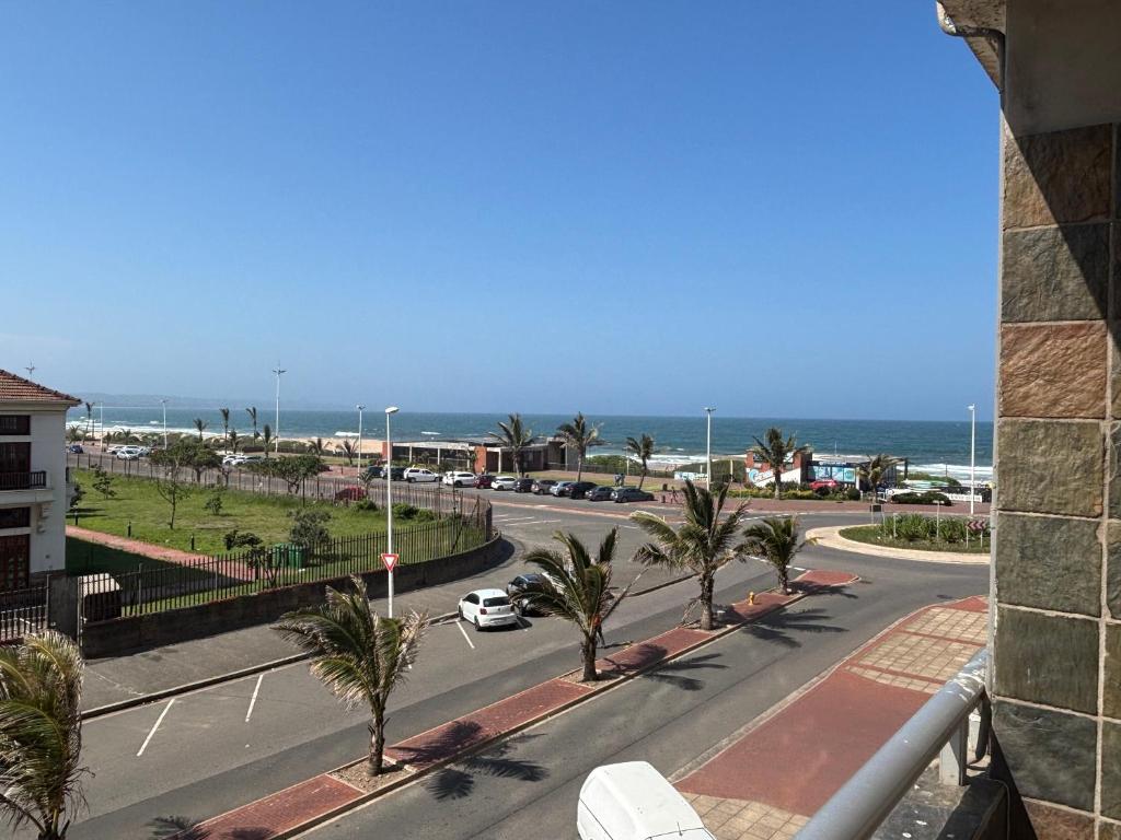 Una vista de una calle con palmeras y el océano. en Tenbury Beach Apartment 208, en Durban