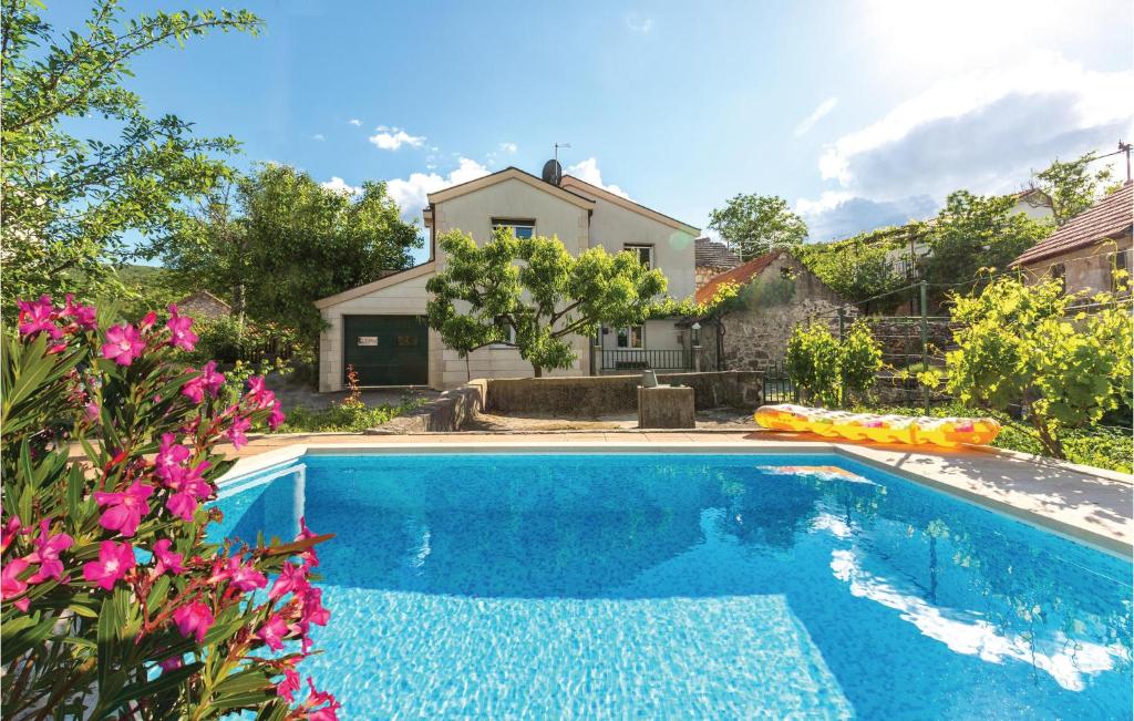 a swimming pool in front of a house with flowers at Two-Bedroom Holiday Home In Slivno in Slivno
