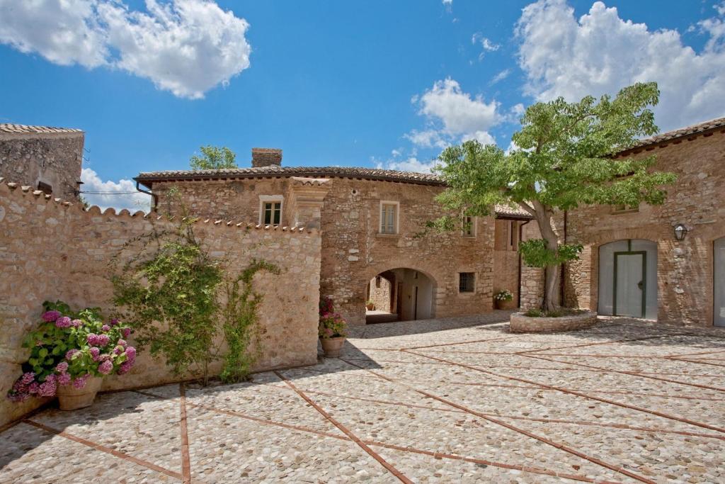 an external view of a stone house with a courtyard at Borgo Della Marmotta in Spoleto