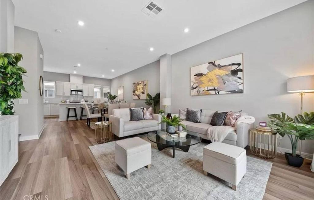 a living room with white furniture and a kitchen at 1311WCara in Anaheim