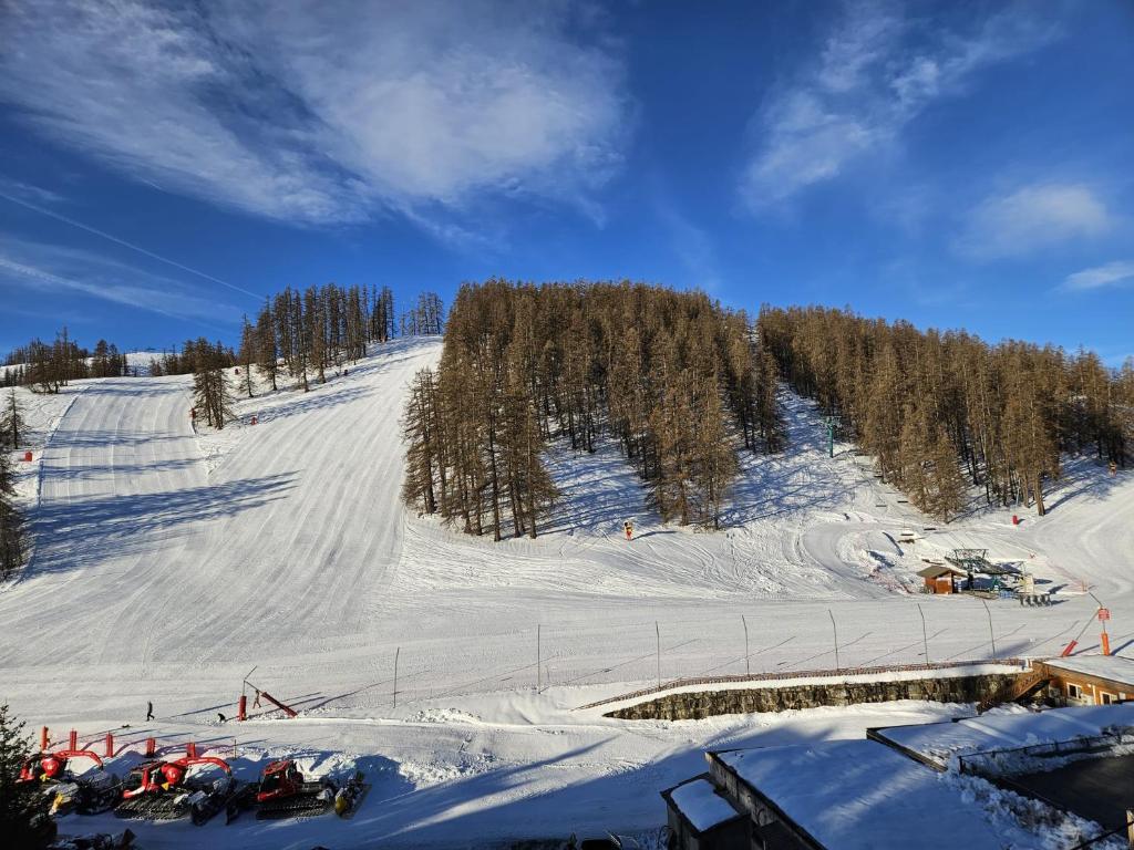 a snow covered ski slope with cars parked on it at Deux pièces face aux pistes in Péone