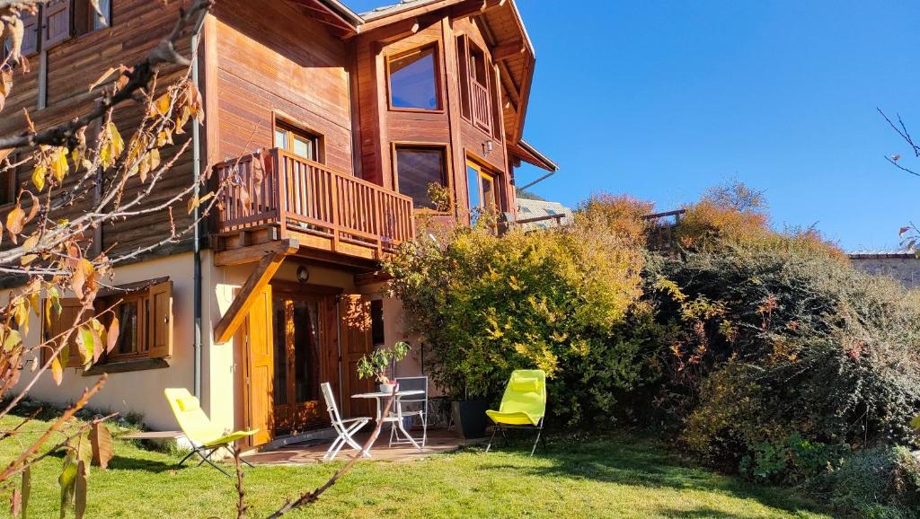 a house with a balcony and chairs in the yard at Chalet Bon Accueil in Briançon