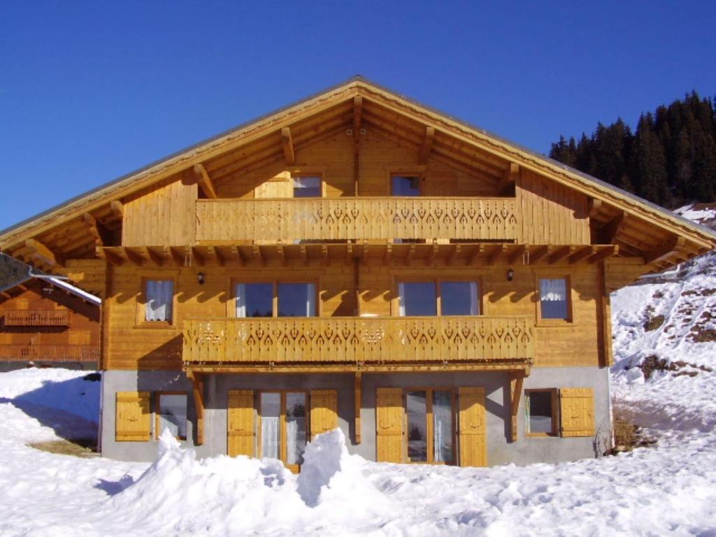 un grand bâtiment en bois avec de la neige au sol dans l'établissement Chalet la Chaumière, à Hauteluce