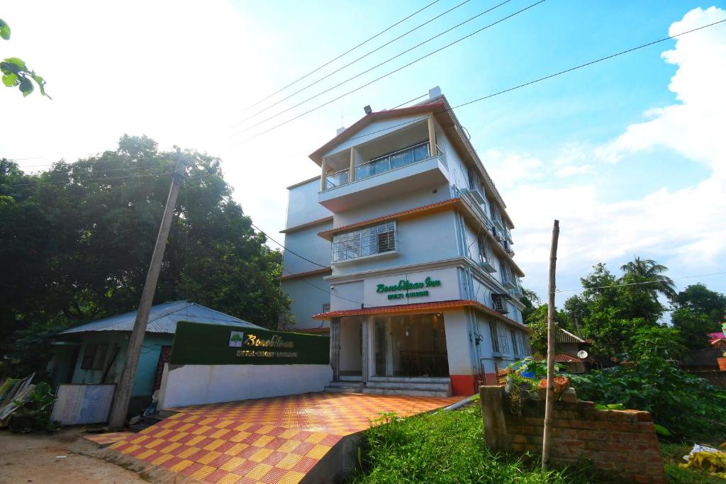 a tall white building with a sign on it at Bonobitaan Hotel & Restaurant in Srī Niketan