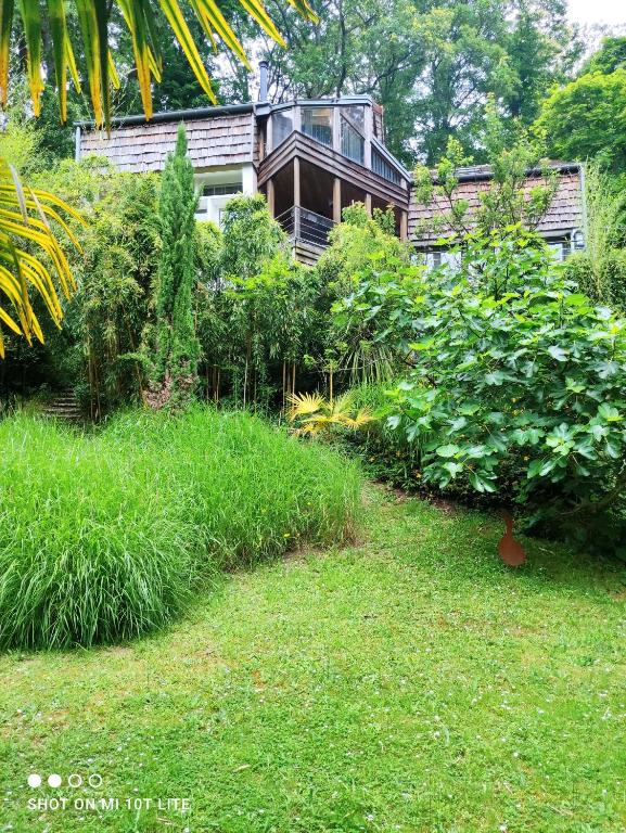 un jardin avec une maison en arrière-plan dans l'établissement Maison des Bois, à Bièvres