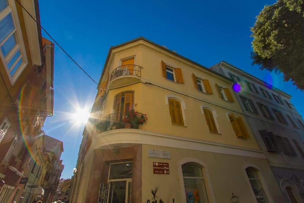 un bâtiment jaune avec un balcon dans une rue dans l'établissement Apartment Spagnolo City, à Pula