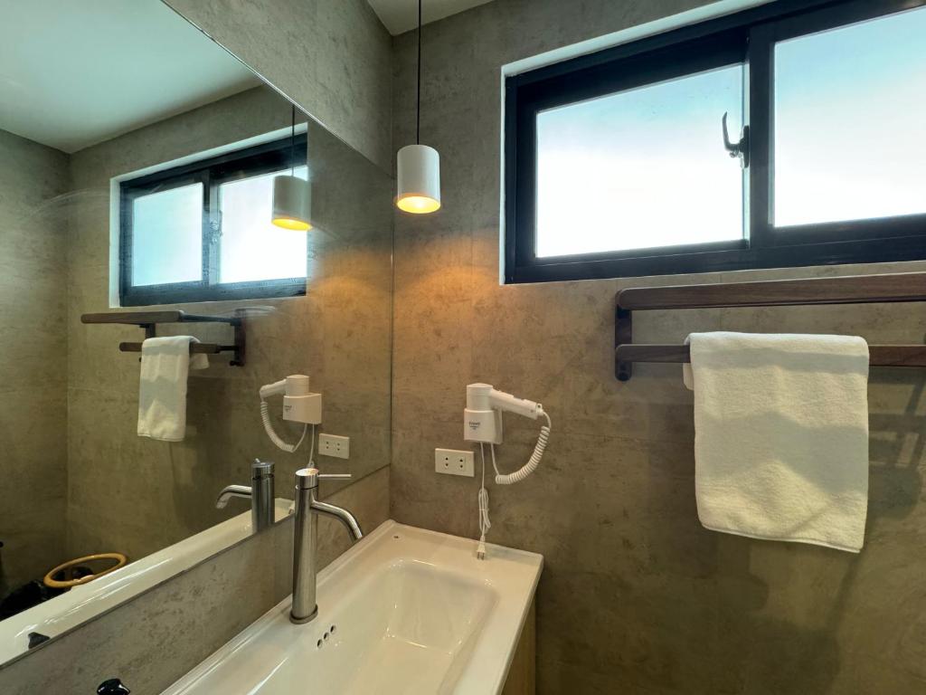 a bathroom with a sink and a mirror and two windows at Caracoa Resort in General Luna