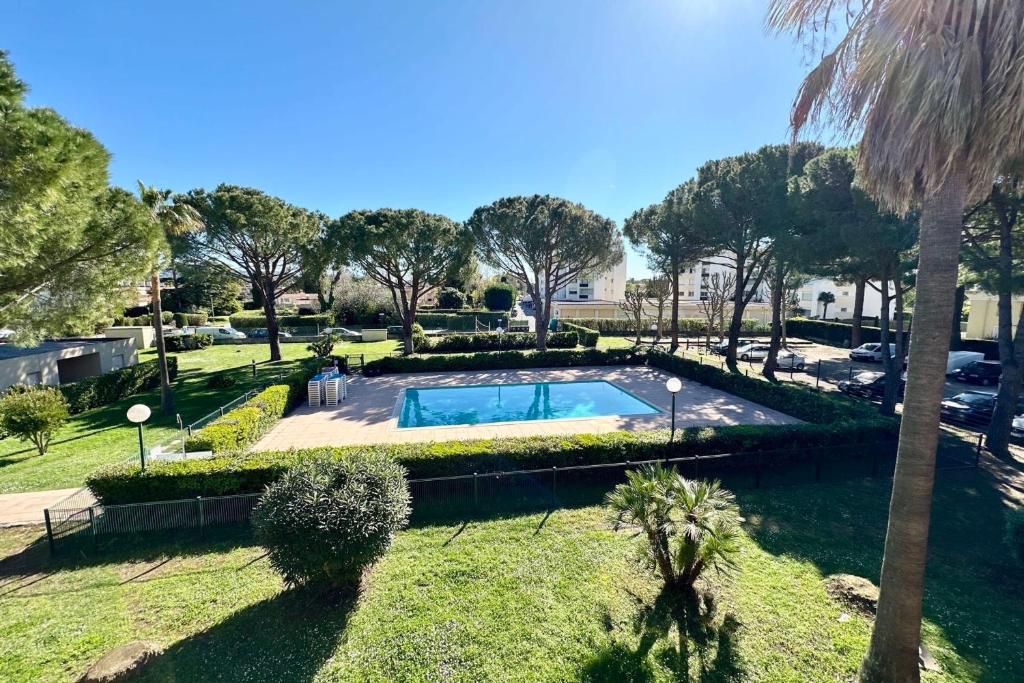 - une piscine dans un parc avec un palmier dans l'établissement Modern apartment with swimming pool in Mandelieu, à Mandelieu-la-Napoule